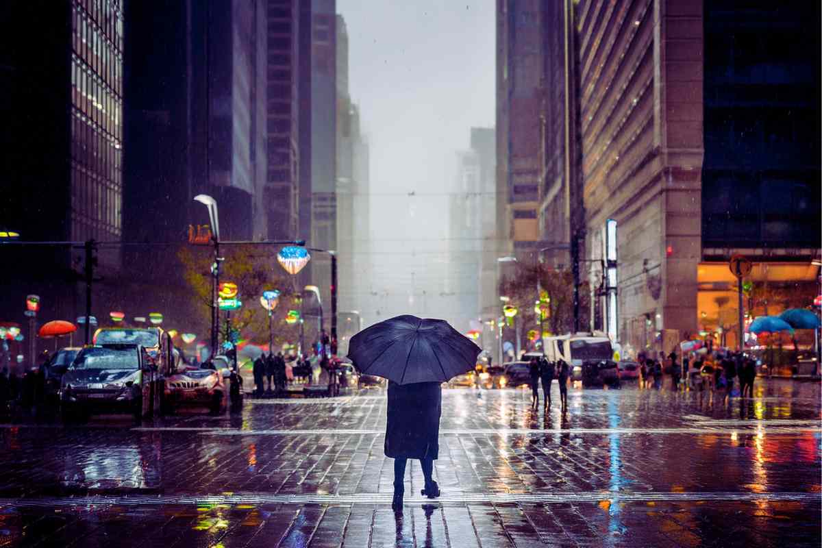 persona sotto la pioggia con un ombrello in una grande città
